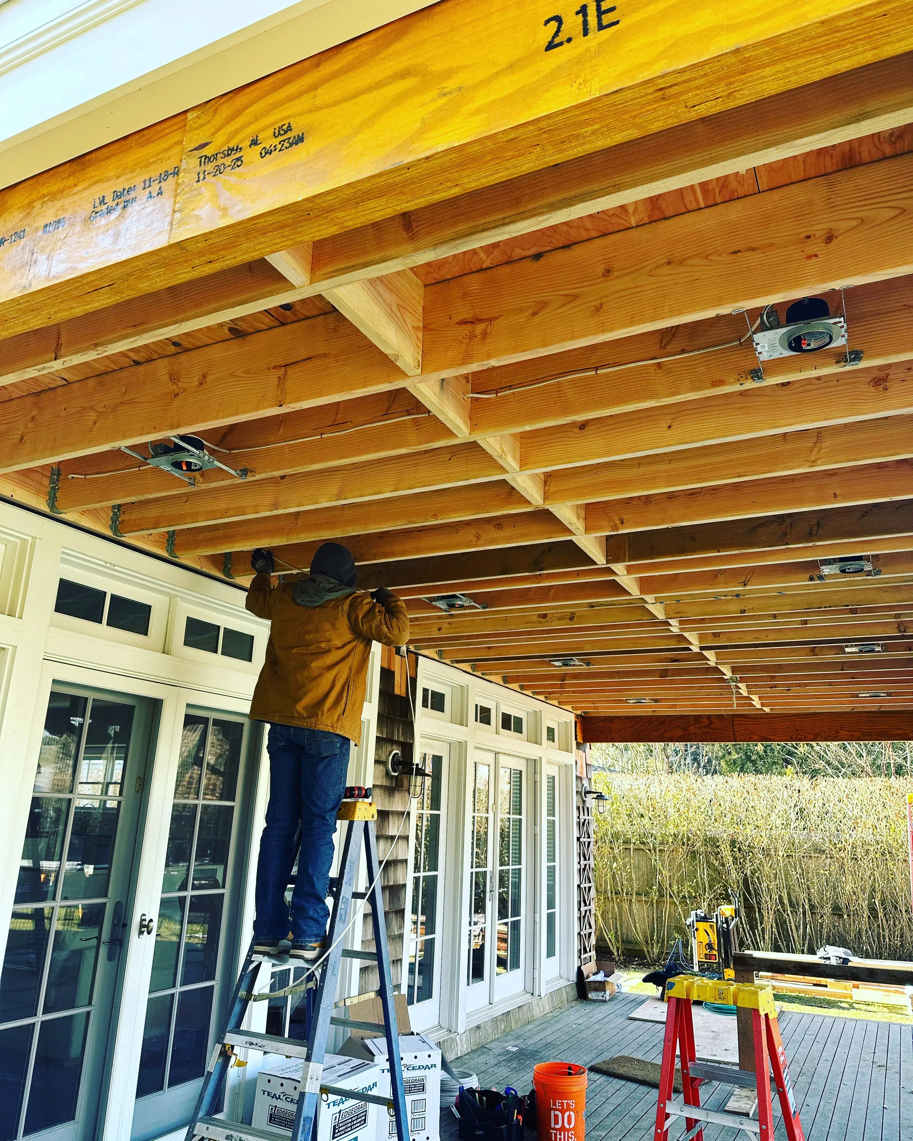 Electrician roughing in wiring beneath exposed framing during a residential renovation